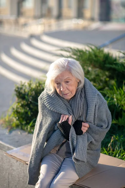 Γκρίζα μαλλιά άστεγη γυναίκα αισθάνεται κρύο και δυστυχισμένη — Φωτογραφία Αρχείου