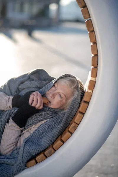 Povero pensionato mangiare cracker mentre sdraiato su panchina — Foto Stock