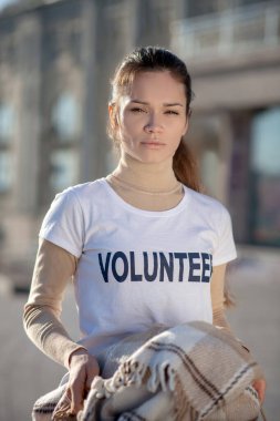 Beyaz tişört giyen siyah saçlı kadın gönüllü olarak çalışıyor.