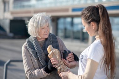 Homeless pensioner taking some food and tea from kind volunteer clipart