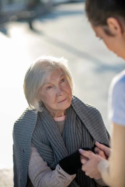 Пожилая бездомная женщина чувствует себя счастливой, разговаривая с волонтером — стоковое фото