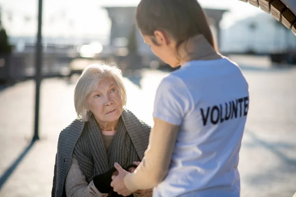 Pensionista idoso sem-teto conversando com voluntário na rua — Fotografia de Stock