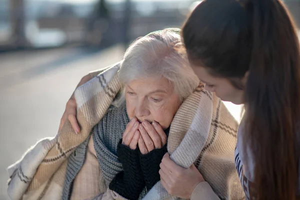 Μελαχρινή γυναίκα που στηρίζει άστεγο συνταξιούχο ενώ φέρνει καρό — Φωτογραφία Αρχείου