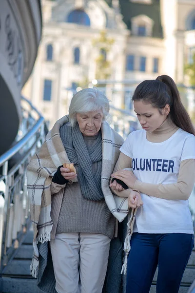 Arme dakloze gepensioneerde voelt zich dankbaar tijdens het lopen met vrijwilliger — Stockfoto