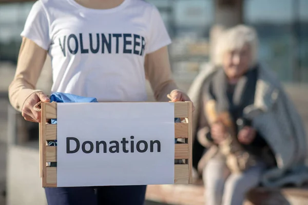 Close up of young kind volunteer holding box with donation — Stock Photo, Image