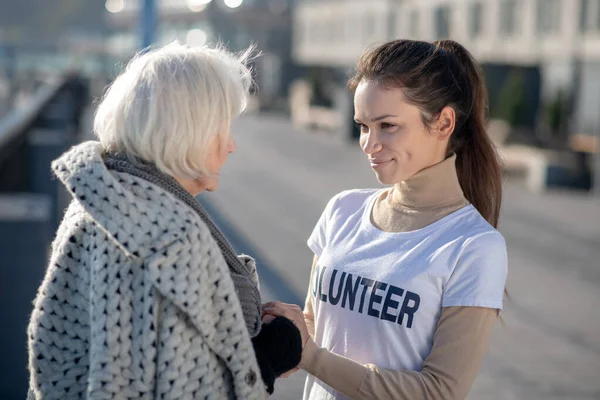 Pensionato senzatetto dai capelli grigi che parla con un volontario per strada — Foto Stock