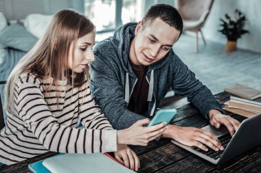 Hoş, pozitif bir adam, kız arkadaşlarının akıllı telefonlarına bakıyor.