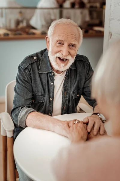 Позитивный пожилой мужчина улыбается, глядя на свою жену — стоковое фото