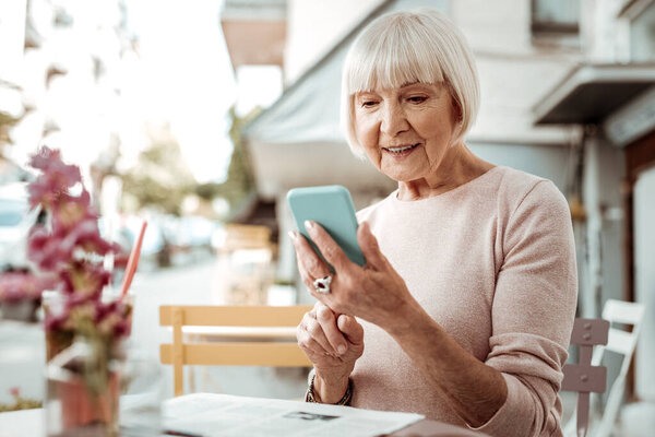 Nice elderly woman looking at her smartphone screen