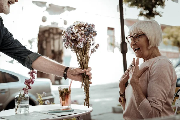 Mulher idosa encantada olhando para as flores — Fotografia de Stock