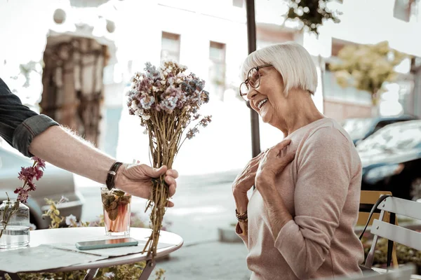 Mulher idosa agradável alegre que recebe flores bonitas — Fotografia de Stock