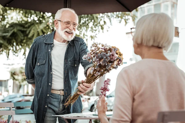 喜びに満ちた男が年配の女性に花を贈る — ストック写真