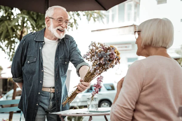Положительный бородатый мужчина дарит цветочный букет — стоковое фото