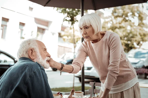 Милая пожилая женщина трогает своего мужа за щеку — стоковое фото