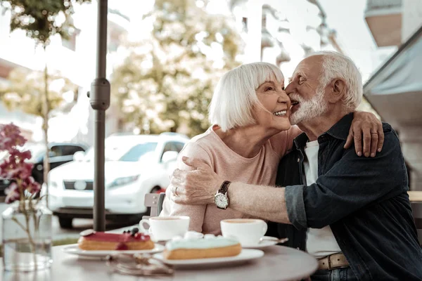 Joyful homem sênior querendo beijar sua esposa — Fotografia de Stock