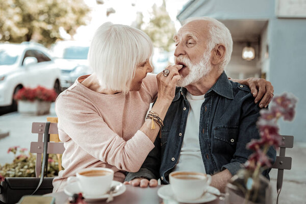 Positive nice senior woman feeding her husband Stock Picture