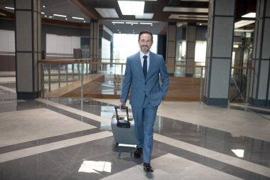 Neşeli sakallı iş adamı iş gezisi sırasında otele giriyor.