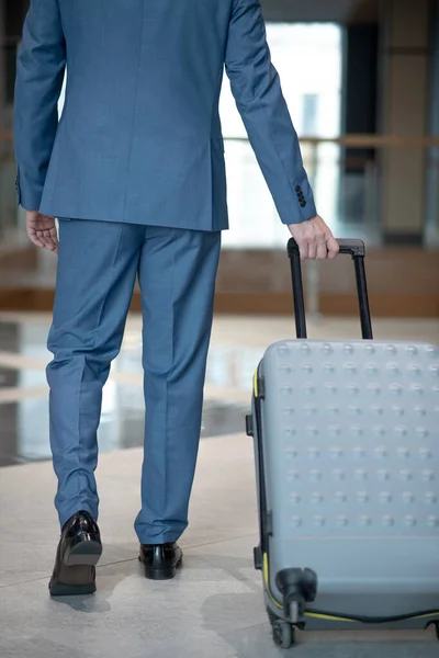 Zakenman draagt zijn grijze bagage tijdens een zakenreis — Stockfoto