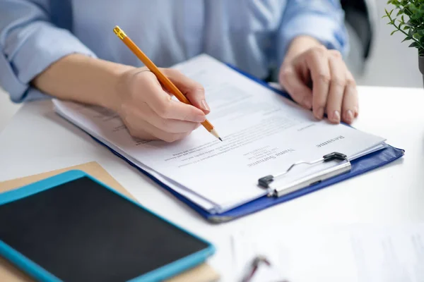 Close up of businesswoman filling tax declaration while sitting at the table — Stock Photo, Image