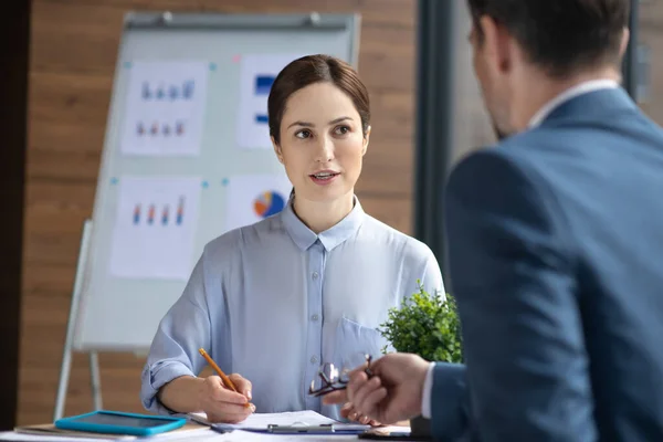 Secretary making notes while listening to her boss giving her tasks for the day