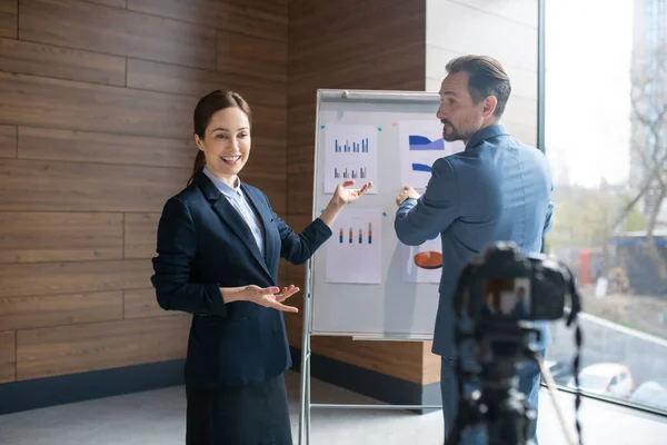 Woman speaking while camera filming her with her business partner