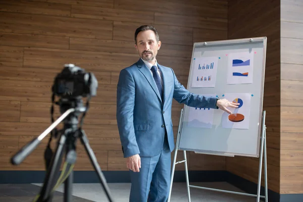Mature affluent businessman standing near smart board and filming blog — Stock Photo, Image