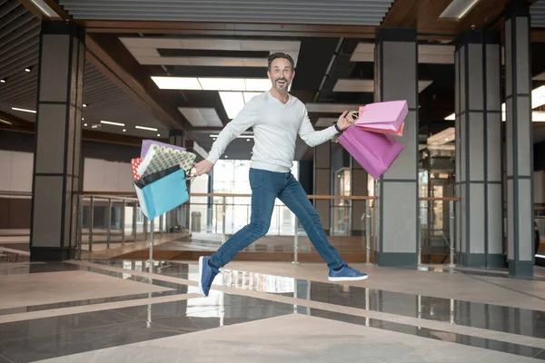 Γενειοφόρος ώριμος άντρας πηδάει ενώ αισθάνεται καταπληκτικά μετά τα ψώνια του Σαββατοκύριακου — Φωτογραφία Αρχείου