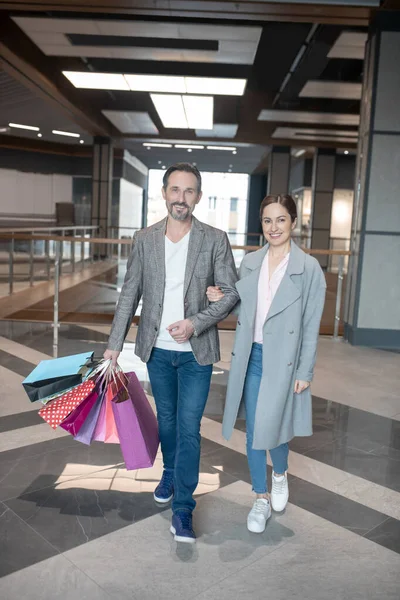 Ζευγάρι χαμογελά φεύγοντας από το εμπορικό κέντρο μετά από επιτυχή ψώνια — Φωτογραφία Αρχείου