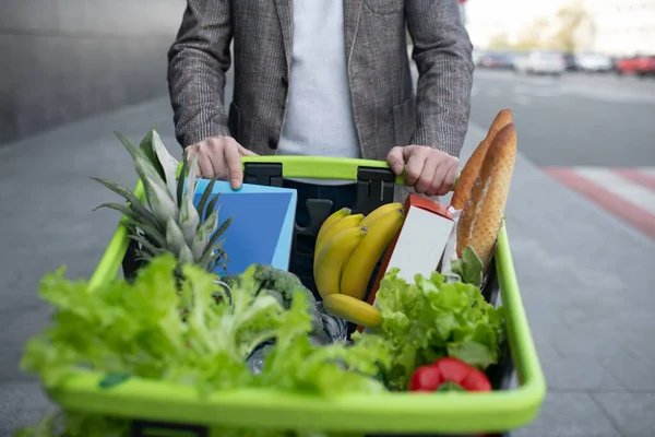 Hombre con chaqueta gris saliendo del supermercado con diferentes alimentos — Foto de Stock