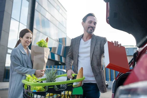 Sorrindo casal colocando seus alimentos no carro após compras compras — Fotografia de Stock