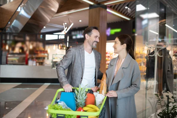 Веселый муж разговаривает с женой, стоя рядом с супермаркетом — стоковое фото