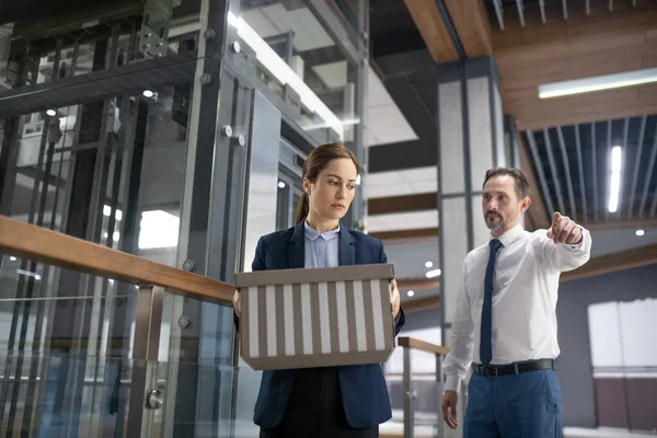 Angry boss shouting and firing young female office worker