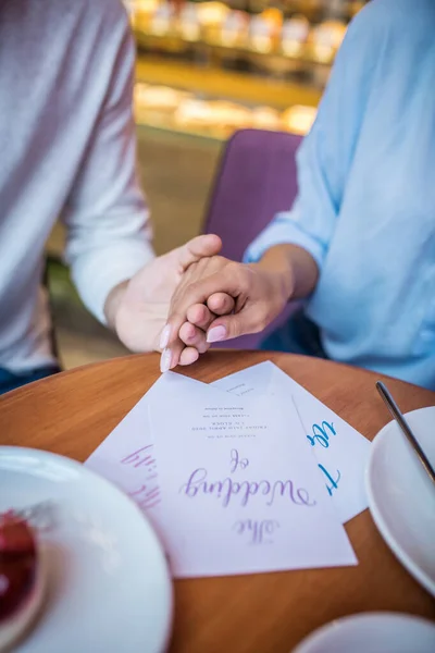 Husband holding hand of his wife while sitting in cafeteria