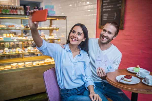 Ζευγάρι κάνει selfie με προσκλήσεις γάμου τους στην καφετέρια — Φωτογραφία Αρχείου