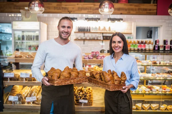 Couple holding boxes with croissants standing in their bakery — Stock Photo, Image