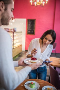 İş kadını menüde çalışırken meyveli keke bakıyor