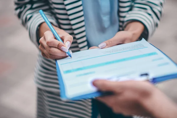 Primer plano de la mujer que pone la firma después de conseguir su paquete — Foto de Stock