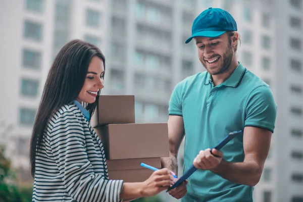 Entrega hombre sonriendo mientras que da declaración a cliente agradable — Foto de Stock