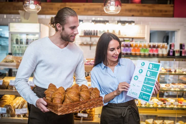 Wife standing near husband while opening bakery with eco products — Stock Photo, Image
