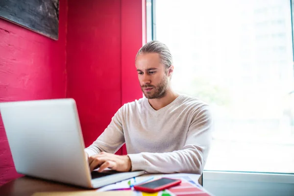 Bärtiger Geschäftsmann arbeitet am Laptop, während er dem Investor SMS schreibt — Stockfoto