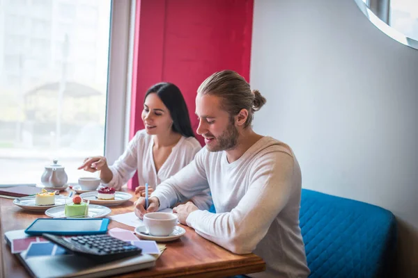 Entrepreneurs having quality check of desserts before opening bakery