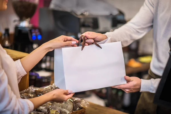 Close up of cashier passing bag with order to the customer — Stock Photo, Image