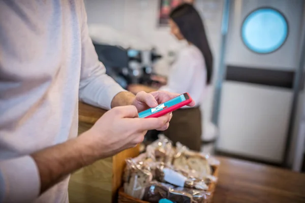 Man checking email on phone while waiting for coffee