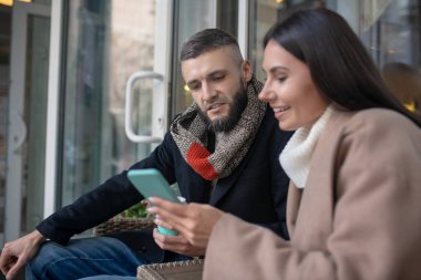 Akıllı telefon ekranına bakan hoş sakallı adam.