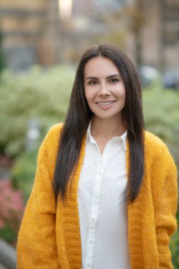 Uzun saçlı neşeli kadın sana gülümsüyor.