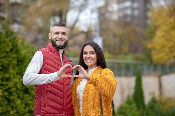 Freudiges junges Paar zeigt dir das Herz — Stockfoto