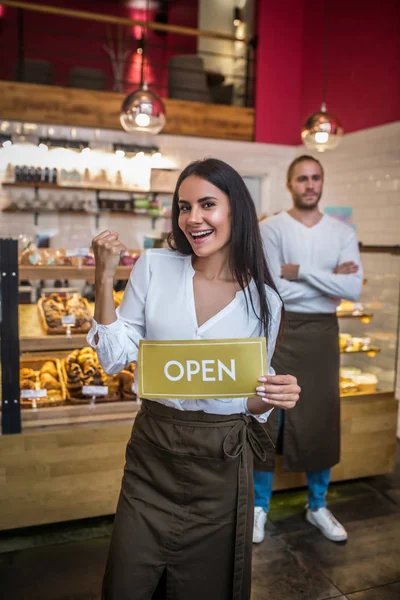 Žena na sobě zástěra otevření pekárny se svým úspěšným manželem — Stock fotografie