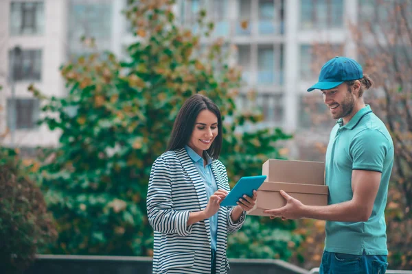 Mujer usando tableta mientras está de pie cerca del hombre de entrega — Foto de Stock