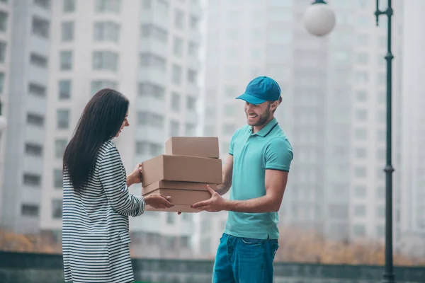 Donna che prende scatole mentre incontra l'uomo di consegna vicino all'edificio — Foto Stock