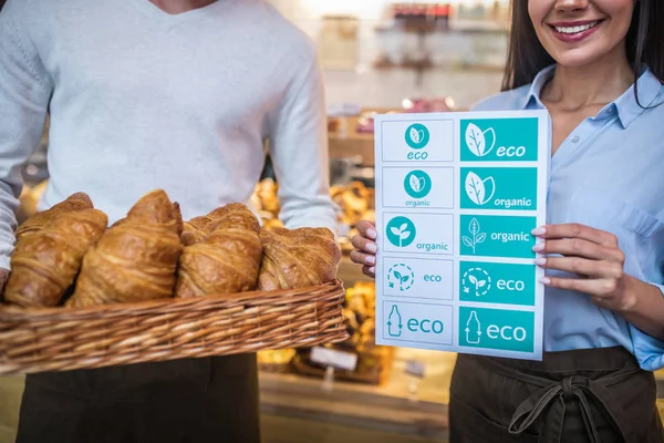 Couple opening eco bakery together and showing croissants